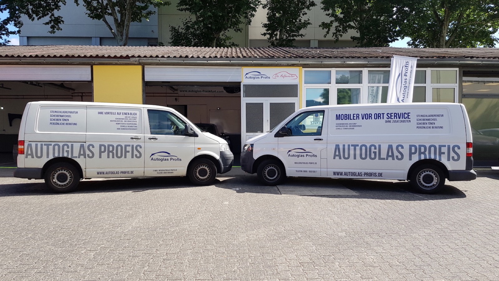 Zwei mobile Einsatzfahrzeuge der Autoglas Profis vor der Werkstatt